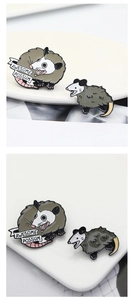 Macro detail of enamel opossum pins featuring Awesome Possum text on white ceramic