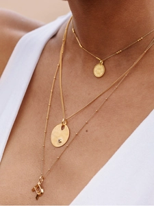 Close-up of layered gold necklaces with textured oval and sparkling crystal pendants
