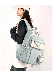 Detail view of light blue backpack with side pockets and a cute bear coin purse charm