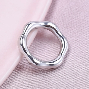 Macro shot of silver wave ring on pink ceramic plate with smooth polished metal finish