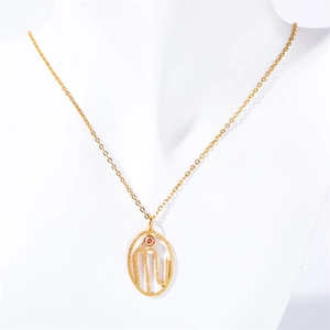 Detail of gold oval zodiac pendant with M letter and pink stone on a white bust
