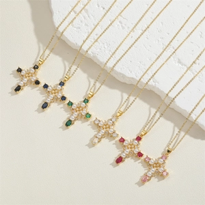 Cross pendant necklace with pearls and multi-color zircons on a white textured stone surface