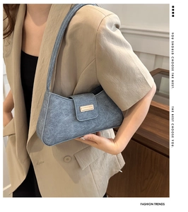 Grayish blue faux suede baguette bag with metal buckle shown in a professional studio setting
