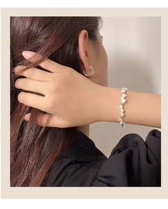 Close-up of baroque pearl bracelet with gold beads and silver hoop earring on a model