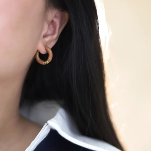 Close-up of model wearing French caramel enamel hoop earrings in 18K gold plated steel