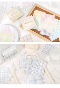 Detail of plaid memo pads in yellow and pink colors on a cork board background