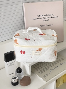 Detail of white quilted bear pattern makeup bag with cute red bows and top handle