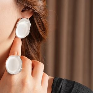Detail showing elegant oval resin ring and earring set in white with silver finish