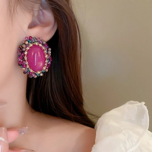 Close-up of vintage oval earrings with magenta crystal and colorful beads on model