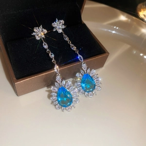 Close-up of sparkling tassel earrings with blue gemstones and zircons in a jewelry box