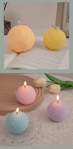 Detailed view of spherical embossed floral scented candles in vibrant colors on a wooden tray