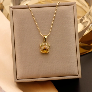 Gros plan du pendentif patte de chat doré avec zircon cœur jaune sur boîte velours