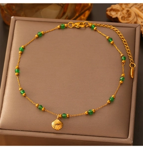 Detail of vintage gold shell pendant anklet with green beads on jewelry box
