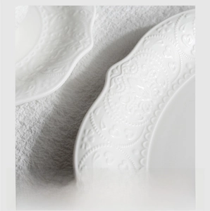 Detail of embossed floral pattern on white ceramic plate with non-slip polished base