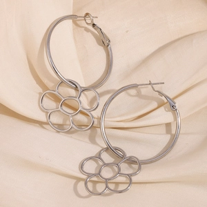 Détail de boucles d'oreilles pendantes fleurs argentées sur tissu en soie beige élégant