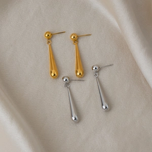Détail élégant de boucles d'oreilles pendantes en forme de goutte en or et argent poli