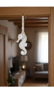 Macro shot of seahorse wall hanging with cream wooden body and small golden bell