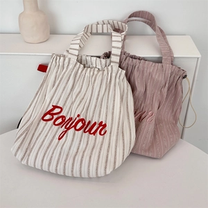 Close-up of cream and lilac striped canvas tote bags with Bonjour letter embroidery