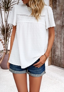 Close-up of white short-sleeve top featuring 3D dot texture and delicate lace stitching