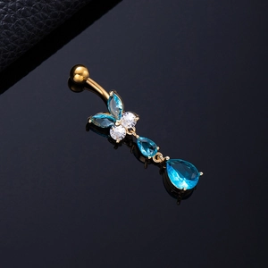 Macro shot of gold butterfly belly ring with blue and white zircons on black mirror