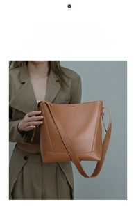Detail of caramel leather bucket bag texture and reinforced stitching on wide shoulder strap