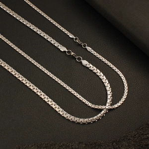 Three silver stainless steel square link chains with lobster clasps on dark textured background