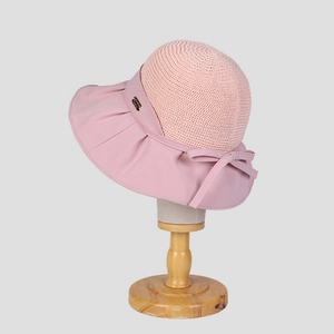 Detail of pink summer sun hat with knit crown, fabric brim and a bow with a gold plaque