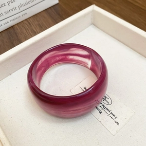 Detail of wide resin bangle featuring magenta marble texture on cream display tray