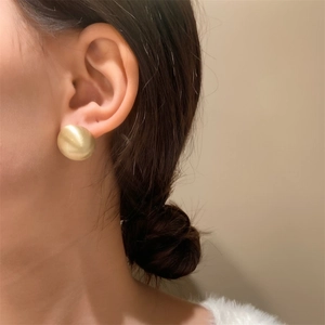 Close-up of matte gold button earrings on model showing vintage brushed texture
