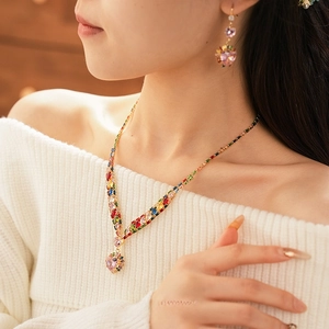 Golden necklace and earring set with colorful zircon heart pendants worn by a model
