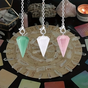 Natural crystal hexagonal pendulum pendants in pink and green on a divination board