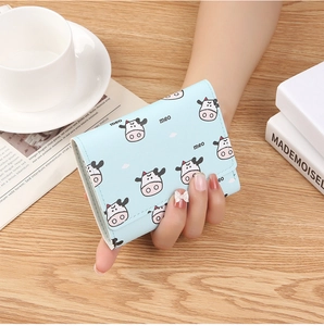 Detail of light blue tri-fold mini wallet featuring a cute cow pattern and smooth PU leather