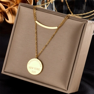 Détail d'un collier multicouche en acier inoxydable doré avec pendentif rond dans son coffret