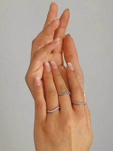Close-up of stacked wavy thin rings with multi-color stones on model finger