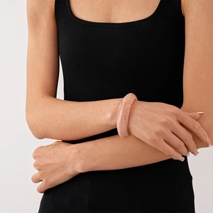 Detailed close-up of textured beige acrylic bangle with spiral patterns on model wrist