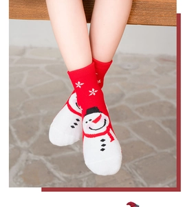 Close-up of red Christmas kids socks featuring knitted white snowman and snowflake patterns
