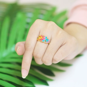 Detail shot of colorful leaf ring with enamel finish on woman's hand in tropical setting