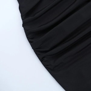 Détail d'une robe moulante noire avec des fronces et des textures de tissu fines