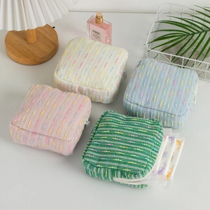 Detail of striped knitted cosmetic bags in four pastel colors with zipper closure