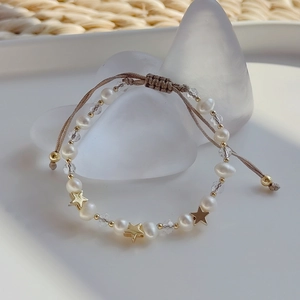 Detail of woven bracelet with natural freshwater pearls and gold star charms