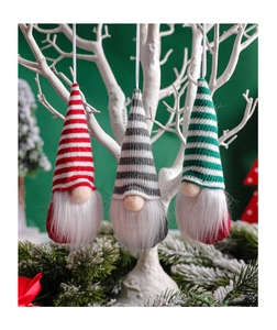 Three knitted Christmas gnomes with striped hats hanging on white branches for decor
