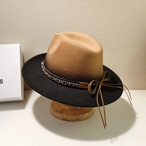 Detail of felt jazz hat with brown crown, black brim, rhinestone band and leather bow