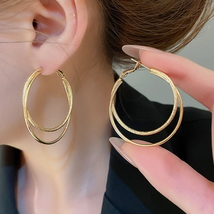 Close-up of 18k gold plated double hoop earrings showing layered texture on ear model
