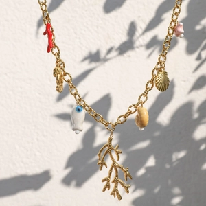 Gold ocean beach necklace featuring coral sea horse and shell charms on metal chain