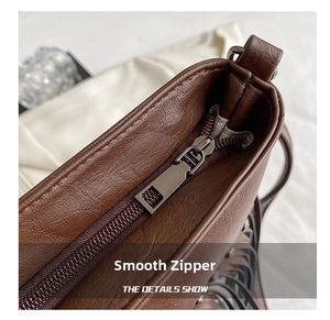 Détail de la fermeture éclair en métal argenté sur un sac en cuir marron foncé grainé