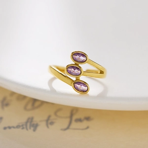 Macro detail of triple purple zircon stones on a gold-plated stainless steel wrap ring