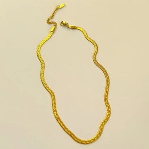 Gros plan sur la chaîne serpent dorée montrant la gravure 18K sur l'étiquette du fermoir