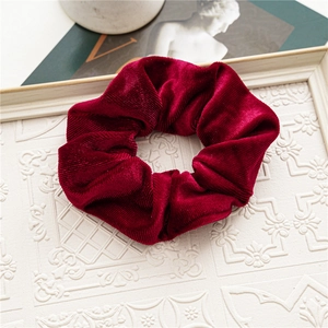 Close-up of deep wine red velvet scrunchie with striped texture on vintage white frame