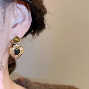 Close-up of vintage golden heart earrings with tiger eye stone worn by a model