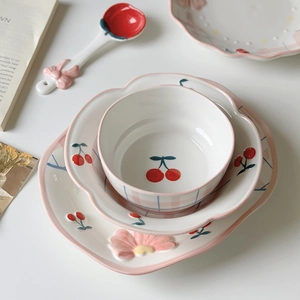 Detailed close-up of hand-painted pink floral ceramic bowl and plates set for breakfast